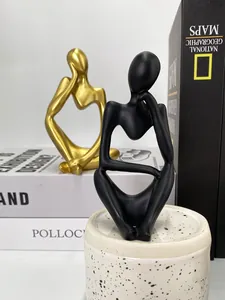 Detail of golden and black thinker sculptures with matte and gloss finish on books