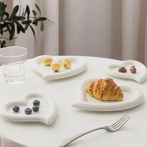 Dettaglio di piatti da dessert in ceramica a forma di cuore con cornetti e mirtilli