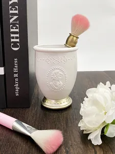 Dettaglio portapennelli da trucco vintage in resina con rilievo floreale e base oro