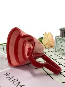 Detail view of heart shaped ceramic mug with red stripes and large heart handle