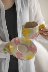 Detail of hand-held vintage floral ceramic coffee cup with irregular artistic shape