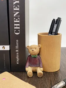 Dettaglio statua di orsetto con maglione viola che tiene un portapenne in resina stile legno
