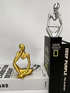 Detailed view of modern thinker statues in gold and silver on books for home decor