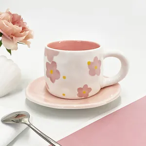 Close-up of elegant floral ceramic coffee cup with matching pink saucer and silver spoon