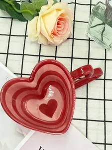 Top view of a red heart-shaped ceramic coffee mug with gradient inner texture on a plaid cloth