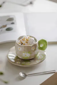 Detail of retro ceramic coffee cup with daisy patterns and green donut handle