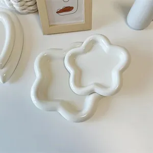 Dettaglio del set da colazione in ceramica bianca con piatti a forma di fiore e nuvola