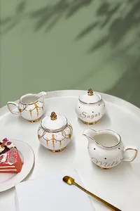 Close-up of elegant ceramic sugar bowl and milk jug with gold rim and embossed texture