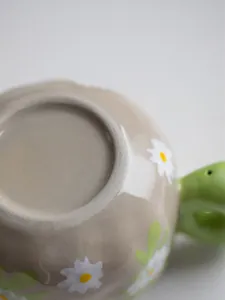Detail of ceramic coffee cup base featuring white daisy patterns and glazed finish