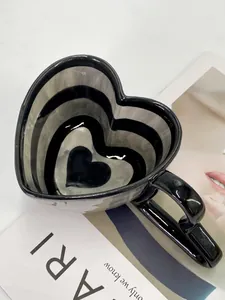 Close-up of heart-shaped ceramic mug with black and white horizontal stripes and wide handle