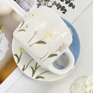 Detail of floral ceramic coffee cup with matching saucer in a garden style setting