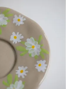 Macro detail of hand-painted daisy pattern on vintage ceramic coffee saucer