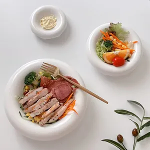 Vista dall'alto di ciotola e piatto in ceramica bianca con insalata e salsa inclusa