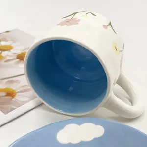 Detailed view of floral ceramic mug with bright blue interior and cloud pattern saucer