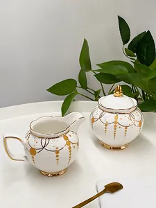 Detailed macro view of European luxury ceramic sugar bowl and creamer set with gold trim