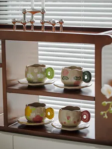 Artistic hand-painted ceramic coffee cups with bold colored handles on a wooden shelf