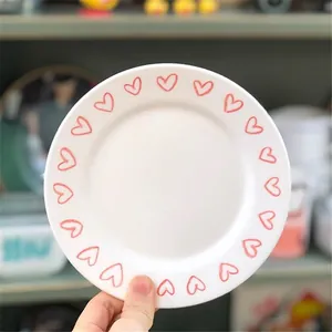 Primo piano di un piatto in ceramica bianca con cuori rossi per la prima colazione