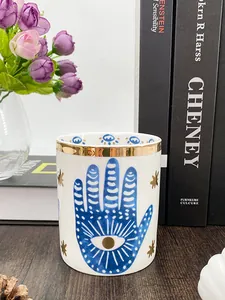 Detail der Keramik-Hamsa-Kerzenschale mit Goldrand und blauem Auge des Bösen im gemütlichen Stil