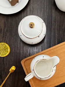 Detail of Nordic ceramic sugar bowl and milk pitcher with black polka dots and gold trim