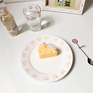 Candela profumata a forma di formaggio su un piatto in ceramica con decoro a cuore