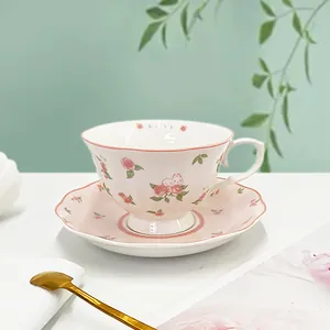 Close-up of ceramic coffee cup with rose and rabbit patterns on a matching saucer