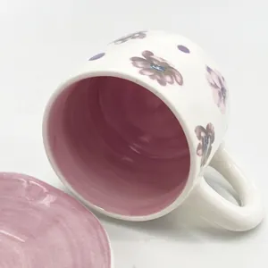 Detailed macro view of hand-painted ceramic coffee cup with purple floral motifs