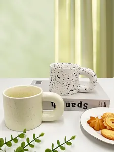 Detail of Nordic ceramic mugs with ink splash patterns and chunky round handles