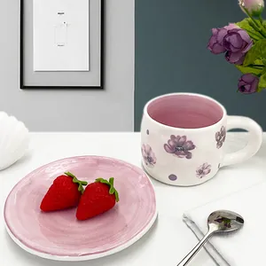 Detail of ceramic coffee cup with purple flowers and pink saucer for afternoon tea