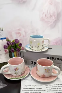 Macro shot of handmade ceramic floral coffee cups with matching saucers in pastel colors