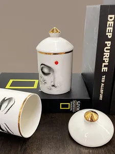Pot en céramique blanc avec visage artistique et poignée dorée sur des livres