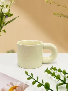 Close-up of cream ceramic mug featuring black ink splatter and thick chunky handle