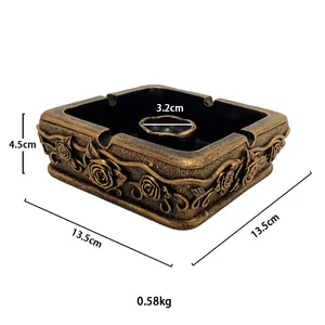 Detail of vintage gold square ashtray with ornate rose reliefs and metallic texture