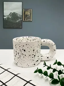 Detail of Nordic ceramic mug with black ink splatter pattern and wide round handle