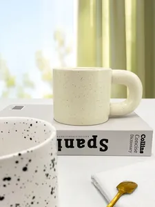 Close-up of Nordic ceramic mug with thick C-shaped handle and speckled glaze finish