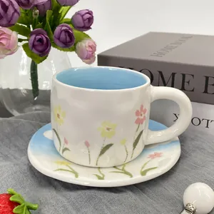 Detail view of hand-painted floral ceramic coffee cup and matching saucer set