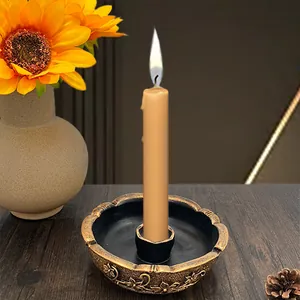 Detail of vintage gold metal candle holder with floral relief and lit cream candle