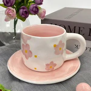 Detail of floral ceramic coffee cup with large round handle and matching pink saucer