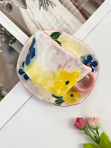Gros plan sur une tasse et soucoupe en céramique peinte à la main avec bords roses