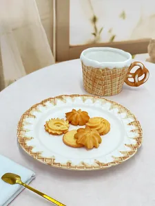 Close-up of ceramic waffle texture mug with pretzel handle and matching cookie plate set