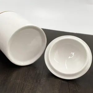 Vue détaillée d'un pot en céramique blanche avec bord doré montrant la base et le couvercle