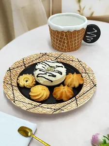 Close-up of waffle-style ceramic plate and chocolate-shaped handle mug on a tea table