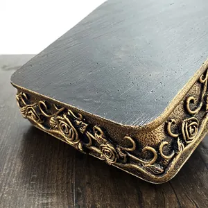 Detailed close-up of vintage golden rose relief on black matte decorative jewelry box