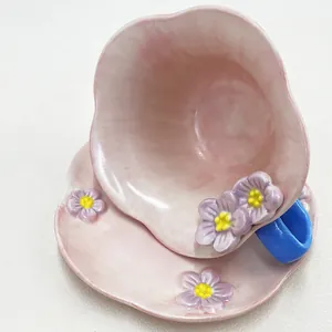 Detail of pink ceramic coffee cup and saucer with 3D floral petals and blue handle