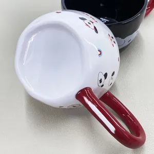 Primer plano de una taza de cerámica blanca con dibujos de animales y asa roja