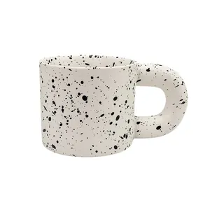 Chubby ceramic mug with ink splash pattern and large round handle on white background
