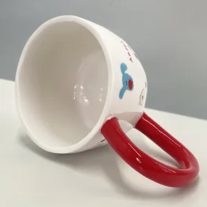 Detalle de taza de cerámica blanca con dibujo animado y asa roja grande ergonómica