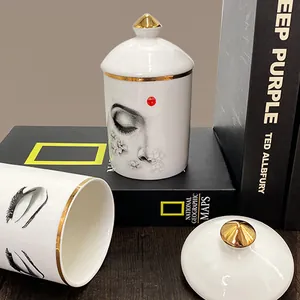 Pot à bougie en céramique blanche avec motif visage et liseré doré sur fond sombre