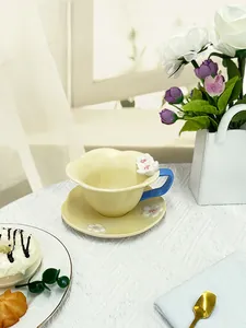 Detailed macro view of cream yellow ceramic coffee cup with blue handle and 3D floral relief