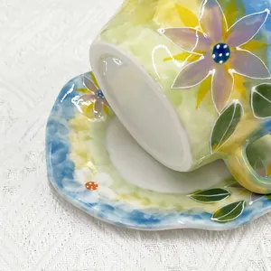 Détail d'un ensemble tasse et soucoupe en céramique peinte à la main aux fleurs violettes