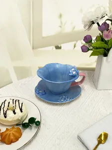 Detailed macro of ceramic teacup with 3D floral accents and wavy edge in blue and pink
